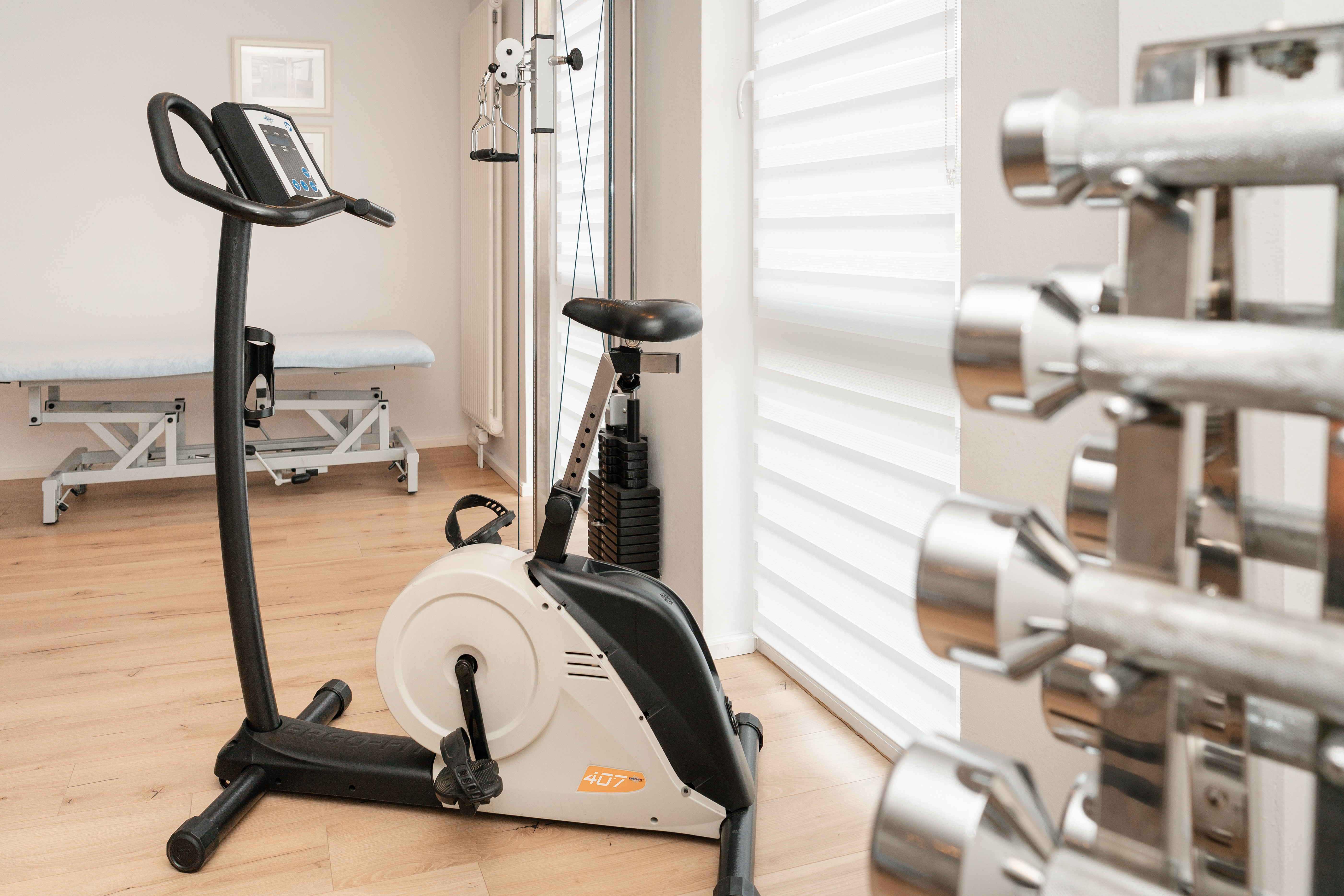 Trainingsbereich mit Ergometer, Hanteln und Seilzug
