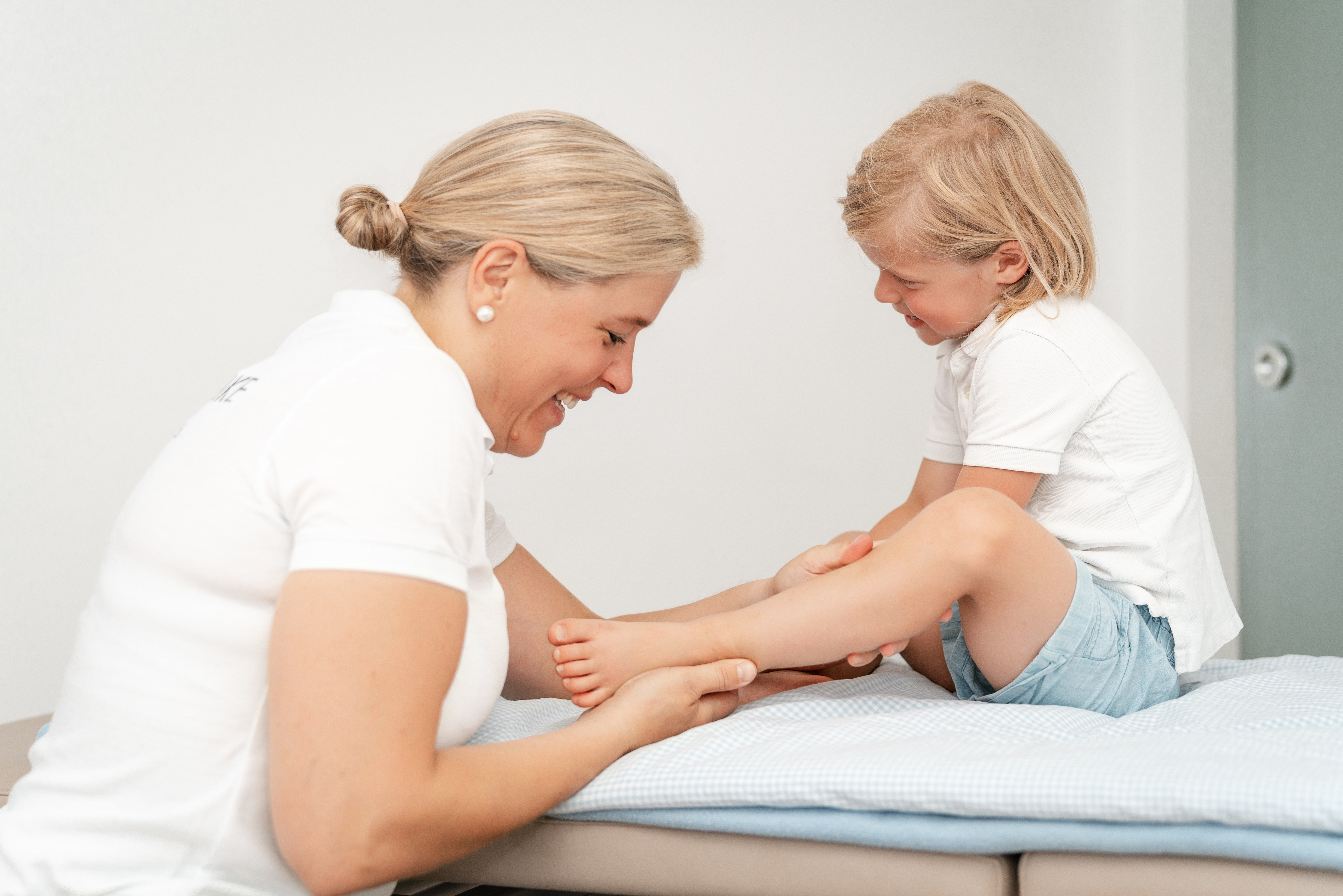 Physiotherapeutische Bewegungsübung mit einem Kind auf der Behandlungsliege
